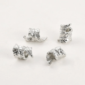 Detailed view of four silver feather-patterned metal spacer beads with intricate engraving