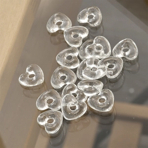 Makroansicht transparenter Glasperlen in Herzform mit Loch für DIY-Schmuckherstellung