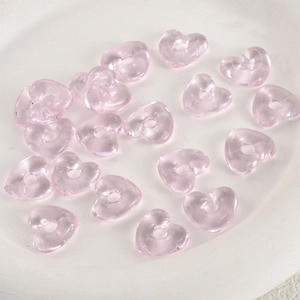 Makro-Detail von transparenten hellrosa herzförmigen Glasperlen für DIY-Schmuckherstellung