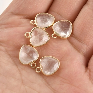 Macro shot of five faceted crystal heart pendants with gold plated edges held in hand