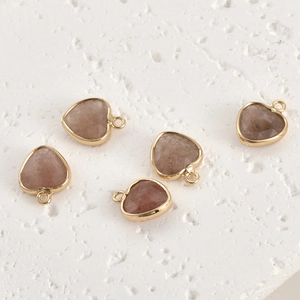 Detailed view of 5 faceted heart stone pendants with gold-plated edges for DIY jewelry