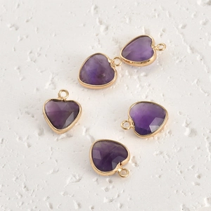 Detailed view of five faceted purple crystal heart pendants with gold plated borders