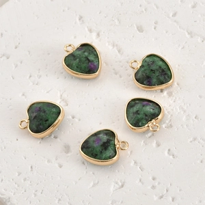 Macro detail of heart-shaped natural crystal pendants with gold edges and green textures
