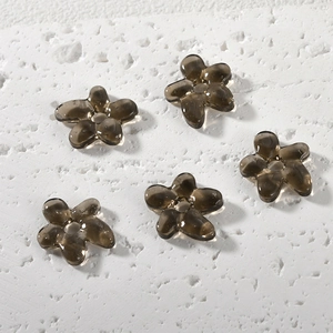 Macro shot of five translucent smoke gray glass five-petal flower beads for DIY jewelry