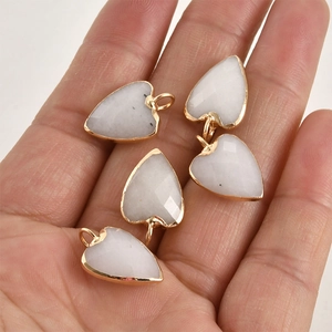 Gros plan de pendentifs cœurs en cristal blanc avec bord doré présentés dans une main