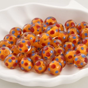 Makroaufnahme von orangefarbenen Lampwork-Glasperlen mit bunten Punkten für DIY-Schmuck