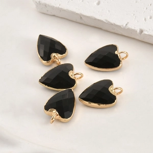 Détail de cinq pendentifs coeur en cristal noir facetté avec bords en métal doré