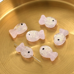 Pink translucent fish beads with glitter for DIY jewelry making in a golden tray