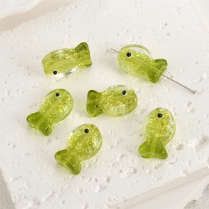 Close-up of green glass fish beads with gold foil and central holes for jewelry making