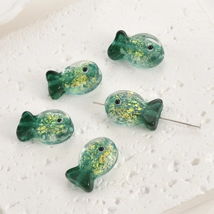 Macro detail of fish-shaped green glass beads with gold foil for DIY jewelry making