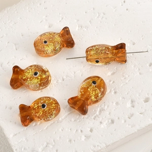 Macro detail of amber fish-shaped glass beads with gold foil for DIY jewelry