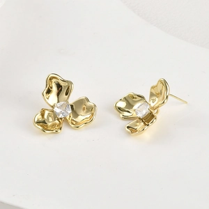 Dettaglio macro di orecchini a trifoglio placcati oro 14k con zircone quadrato