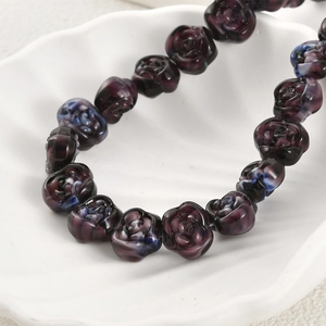 Macro detail of handmade purple glass rose beads with blue swirl gradient texture