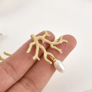 Golden coral branch pendant with drop pearl on finger, 14k gold plated jewelry accessory