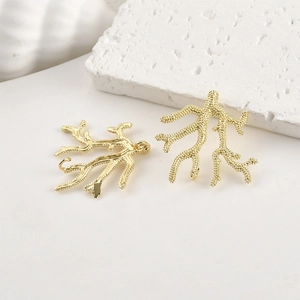 Detailed view of 14k gold-plated coral branch pendants on minimalist white stone