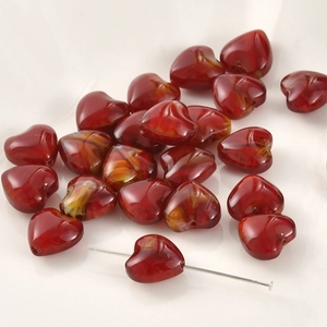 Macro-opname van hartvormige glazen kralen met rood-oranje krul voor DIY-sieraden