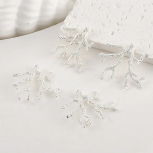Detailed view of four silver coral branch charms for DIY jewelry making and crafts