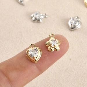 14k gold filled heart and flower charms with zircon inlay held on fingertips