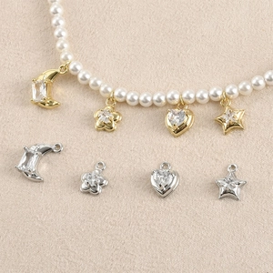 Close-up of 14k gold plated star and moon charms with zircon inlays on pearl necklaces