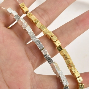Makroaufnahme von vergoldeten und versilberten Lavastein-Würfelperlen für DIY-Schmuck
