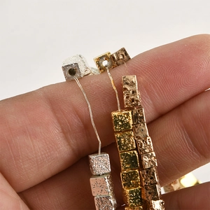 Nahaufnahme von gewürfelten Lavasteinperlen in Gold Silber und Bronze für DIY-Schmuck