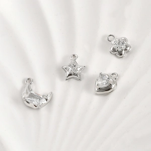 Macro detail of 14k gold-plated moon star heart and flower charms with zircon inlay