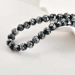 Detailed macro view of black and white snowflake pattern glass beads on ceramic tray