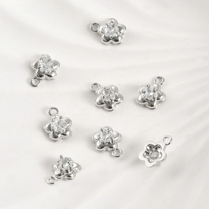Macro shot of silver flower charms with clear zircon inlay for DIY jewelry design