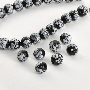 Macro detail of black and white speckled glass beads with smooth polished finish for DIY jewelry
