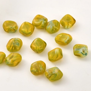 Macro detail of irregular yellow and green marble-textured glass beads for DIY jewelry