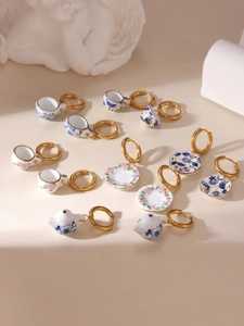 Detail of miniature blue and white porcelain teapot and cup earrings with 18K gold hoops
