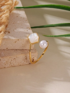 Dettaglio anello in conchiglia placcato oro 18K con perla su lastre di arenaria naturale