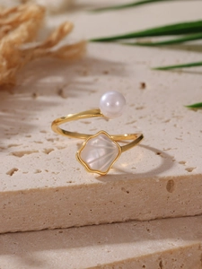Dettaglio dell'anello a conchiglia in oro 18K con perla su una superficie in pietra