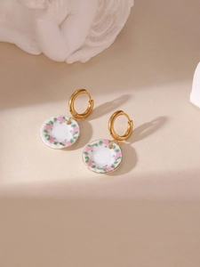 Macro detail of 18K gold-plated earrings with floral blue and white porcelain pendant