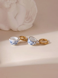 Detail of 18K gold plated hoop earrings with blue and white porcelain mini cup pendants