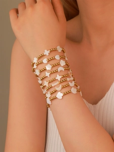 Detail von mehrlagigen Goldperlen-Armbändern mit Kreuz-, Mond- und Stern-Perlmutt-Anhängern