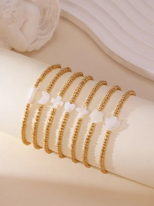 Set of 7 gold beaded bracelets featuring shell pendants like moons and stars on a stand