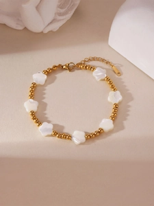 Nahaufnahme des goldenen Perlenarmbands mit Muschelblumen-Anhängern und Karabinerverschluss