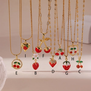 Detail view of 18K gold-plated necklaces with cherry and strawberry enamel pendants