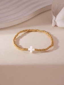 Detail of 18K gold plated beaded bracelet featuring a white shell cross pendant