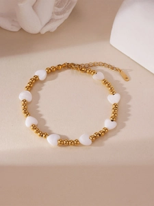 Detailansicht eines Goldperlenarmbands mit weißen Herzanhängern und verstellbarem Verschluss