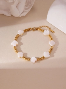 Detail eines 18K vergoldeten Perlenarmbands mit weißen Herzanhängern und verstellbarer Schließe