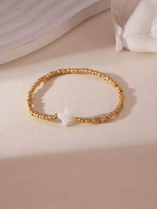 Detailed shot of gold-plated beaded bracelet with star-shaped white shell centerpiece