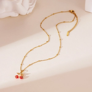 Detail of 18K gold-plated cherry pendant necklace with beaded chain on retro background