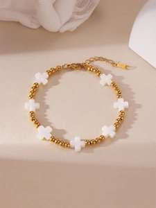 Detailaufnahme des 18K vergoldeten Perlenarmbands mit weißen Muschelkreuzen und Karabinerverschluss