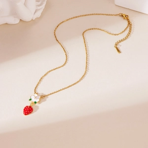 Detail of 18K gold plated chain featuring a white flower and red strawberry pendant