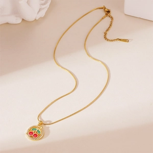 Detailed view of cherry pendant on a gold snake chain with S.STEEL engraved on the tag