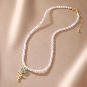 Detail of tulip pendant with blue gemstone and white pearls on champagne silk fabric
