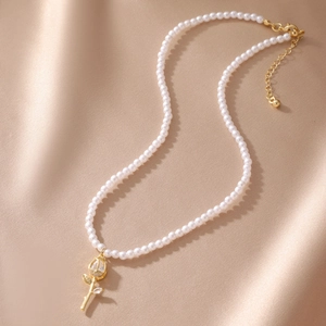 Detail of multi-layer pearl necklace with a gold rose pendant and lobster clasp closure