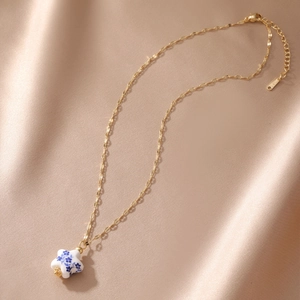 Detail view of gold stainless steel necklace with blue and white porcelain star pendant